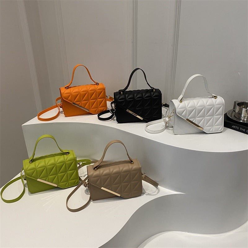 Five handbags in orange, black, white, green, and brown on a white platform with a gray background.